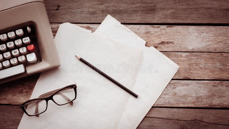 Typewriter, pensil, glasses and paper on wooden background. Creative writing and journalism concept Retro filtered image stock images