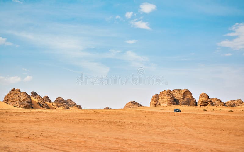 Typical desert landscape in Alula, Saudi Arabia, sand with some mountains, small offroad vehicle, local man and camels