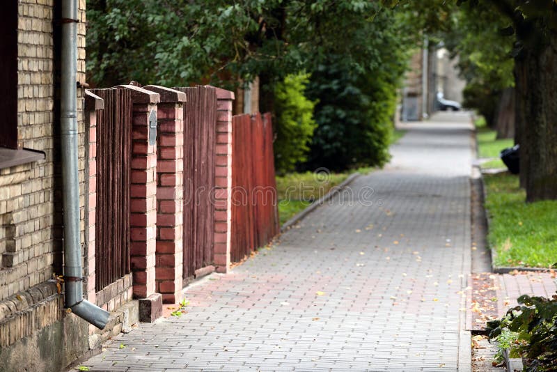 Typical European summer cityscape of old street with paving slabs, brick-walled house, gate and alley in Grodno stock photography Typical European summer cityscape of old street with paving slabs, brick-walled house, gate and alley in Grodno stock photography