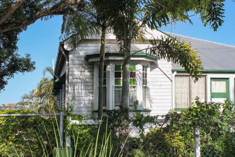 Typical Queensland house with stained glass bay window and palm tree and vines growing on fence with houses on hill in background royalty free stock photos Typical Queensland house with stained glass bay window and palm tree and vines growing on fence with houses on hill in background royalty free stock photos