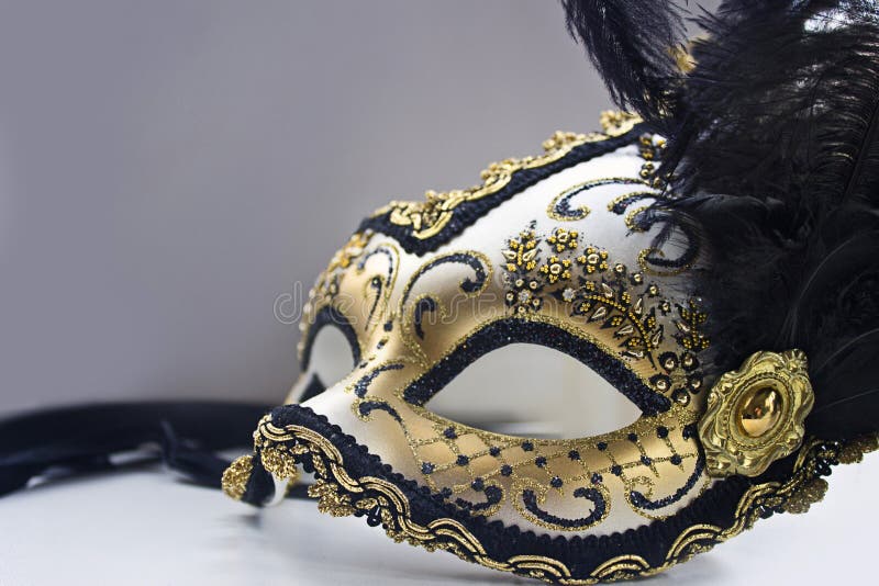 A typical Venetian carnival mask, gold with black, is reflected in the mirror. Looking into a mirror.