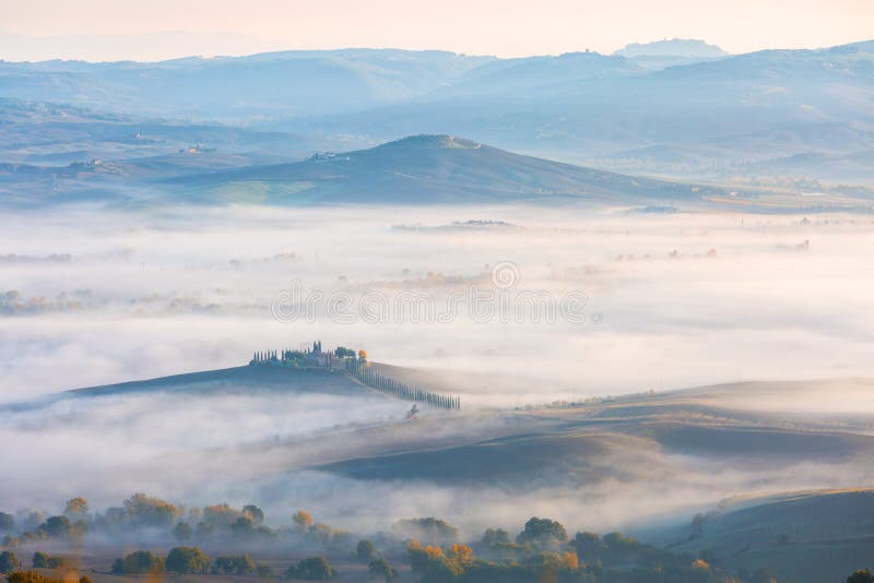 Typical view of Tuscany valley covered with autumn morning fog at dawn near Castiglione d`Orcia , in the Val d`Orcia, Provinc. E of Siena, Tuscany, Italy stock photography Typical view of Tuscany valley covered with autumn morning fog at dawn near Castiglione d`Orcia , in the Val d`Orcia, Provinc. E of Siena, Tuscany, Italy stock photography