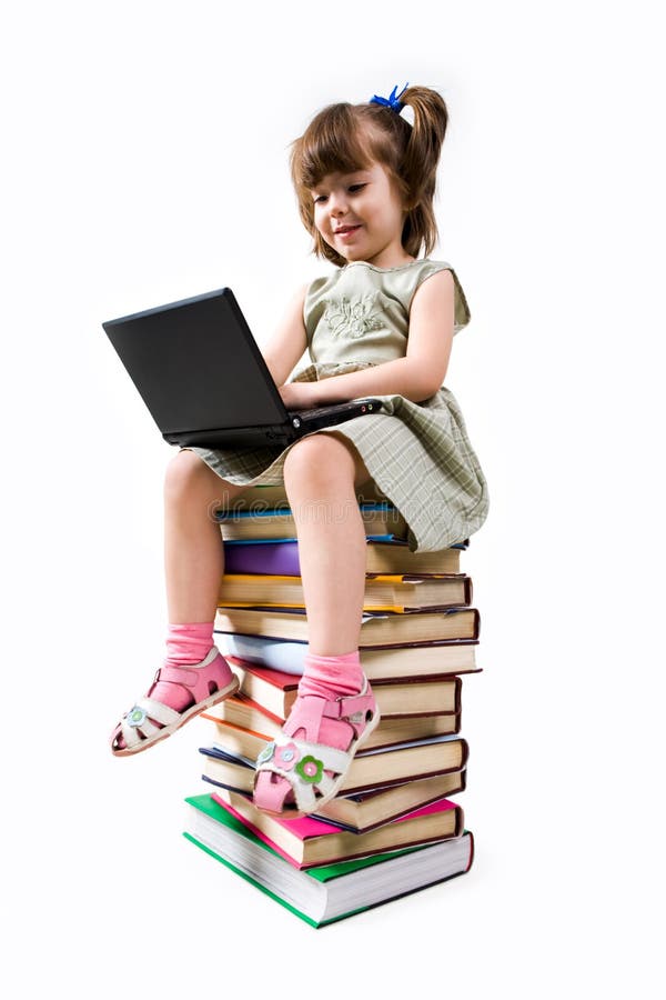 Clever elementary class child sitting on pile of textbooks and typing on laptop