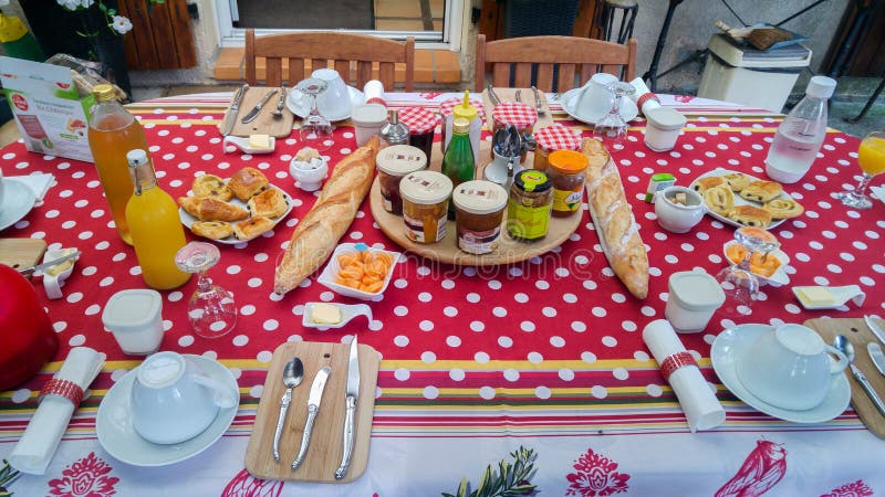 Typisch Frans ontbijt in de Provence Lijst met rood tafelkleed, baguette, jam, kaas, koffie en jus d'orange stock foto Typisch Frans ontbijt in de Provence Lijst met rood tafelkleed, baguette, jam, kaas, koffie en jus d'orange stock foto