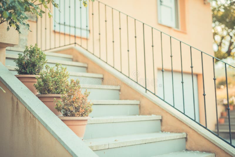 Courtyard of a Mediterranean style house with a marble staircase, blue door and garden with plants. Courtyard of a Mediterranean style house with a marble staircase, blue door and garden with plants.