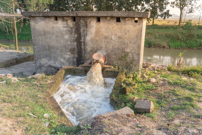 Typiskt asiatiskt bevattningssystem med bubblor som flödar på vatten från en rustik ledning i Vietnam royaltyfria bilder