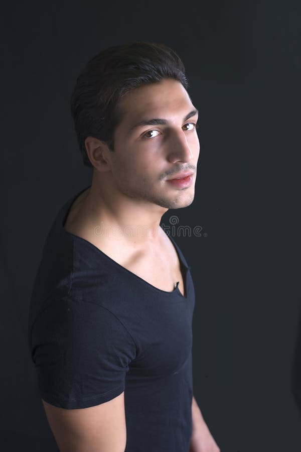 Tânăr cu tricou negru pe fond întunecat stock photos