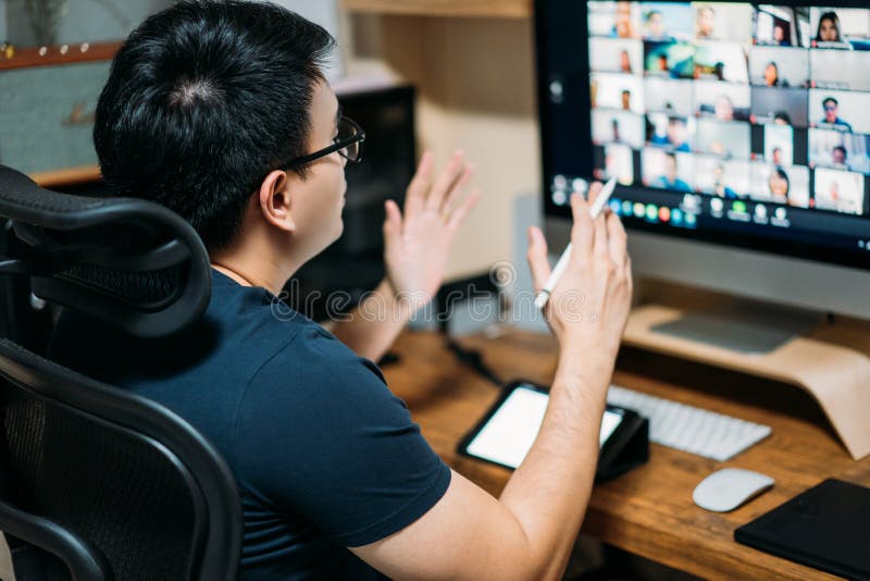 Tânăr om de afaceri asiatic care utilizează un computer pentru o întâlnire de afaceri online cu colegii săi despre planul conferin royalty free stock photos