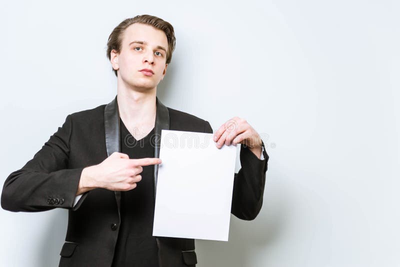Tânăr om de afaceri cu cămașă neagră și blazer, care ține un panou alb și care arată cu degetul spre el. afaceri royalty free stock photos