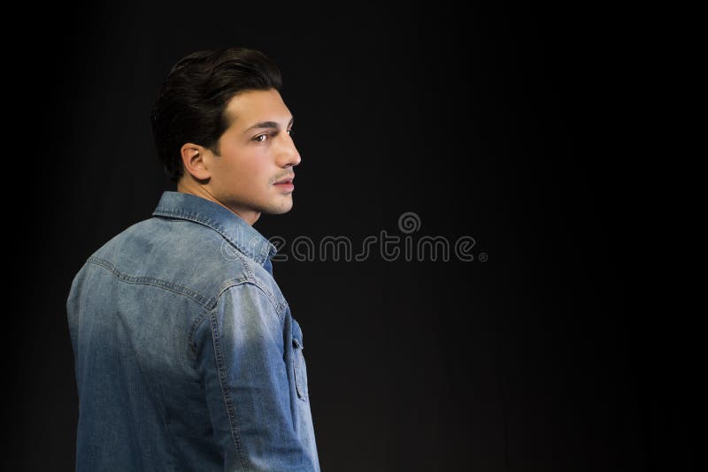 Tânăr purtând bluză denim văzută din spate, uitându-se la o parte stock photo