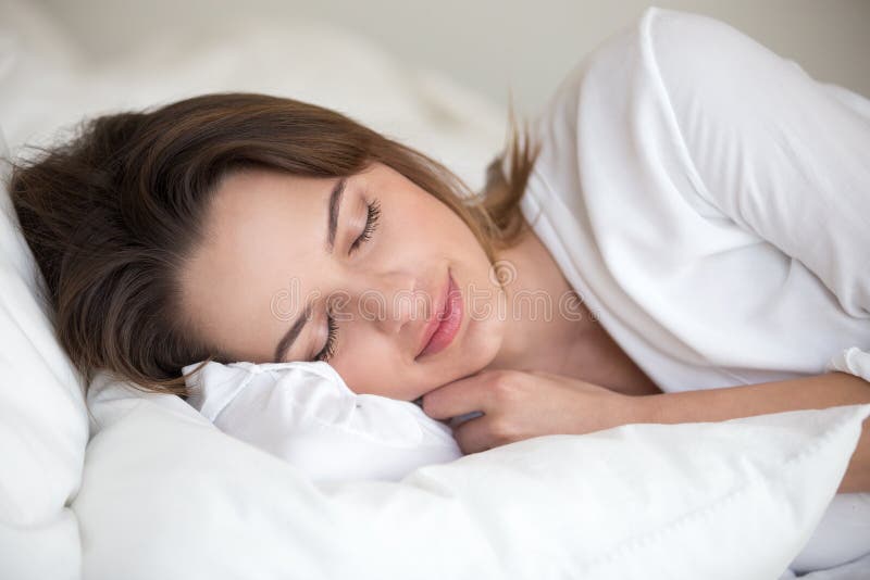 Tânără care doarme bine dormind în pat confortabil stock photos
