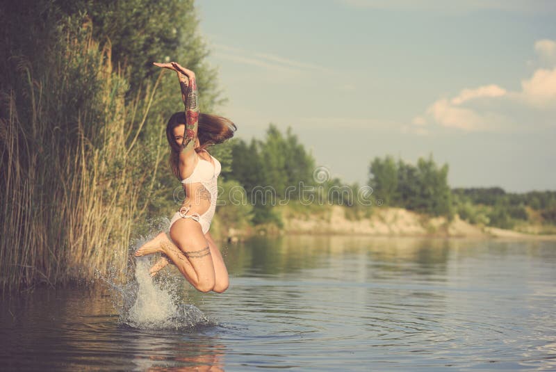 Tätowierte Frau, die vom Wasser springt lizenzfreie stockfotos Tätowierte Frau, die vom Wasser springt lizenzfreie stockfotos