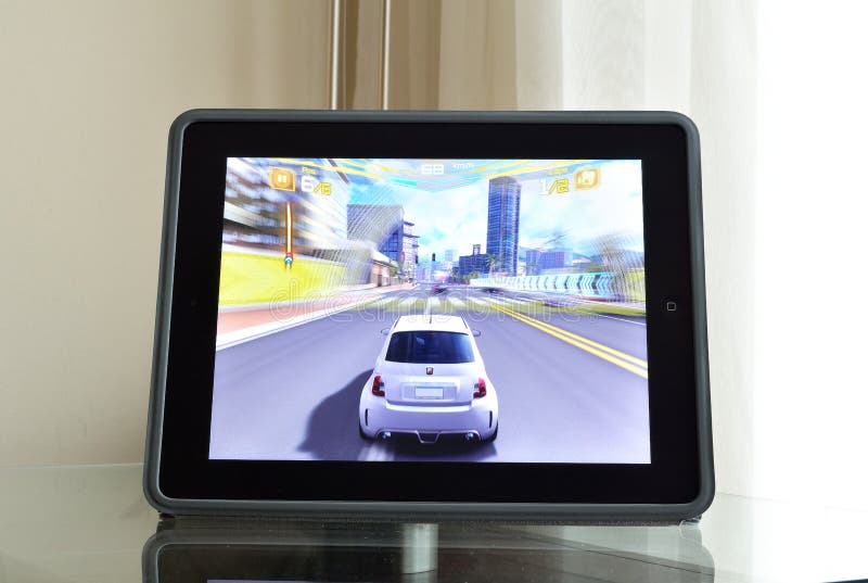 An Ipad 4 with retina display on the glass table with Need for speed game on the screen. An Ipad 4 with retina display on the glass table with Need for speed game on the screen