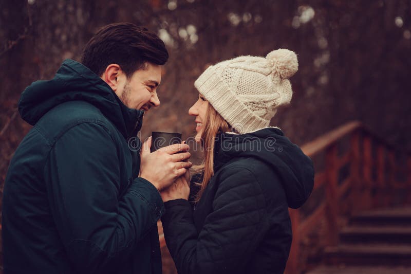 Loving young couple happy together outdoor, drinking tea from thermos, autumn camp, seasonal activities. Loving young couple happy together outdoor, drinking tea from thermos, autumn camp, seasonal activities