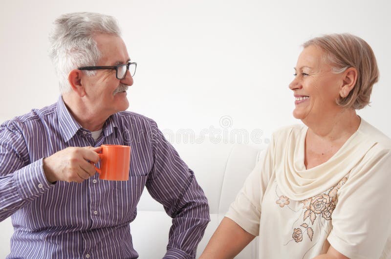 Tè bevente delle coppie senior e felicemente chiacchierare immagine stock Tè bevente delle coppie senior e felicemente chiacchierare immagine stock