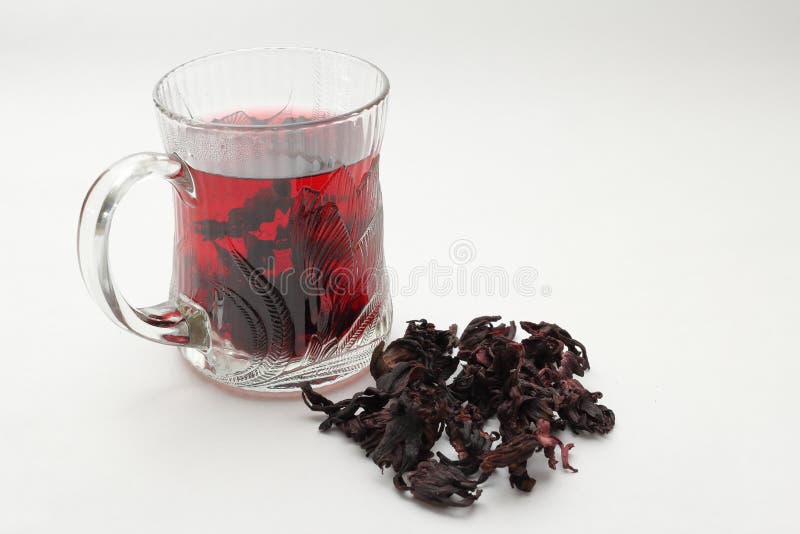 Tè caldo ottenuto con fiori di ibisco essiccati. Tè di fiori di ibisco essiccati in una tazza di vetro su fondo bianco