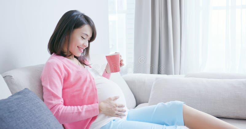 Pregnant woman drink tea and sit on sofa at home. Pregnant woman drink tea and sit on sofa at home