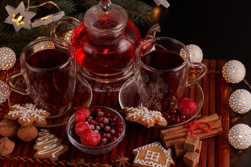 Tè di frutta Composizione per Natale e Capodanno. Ancora vita con due tazze di tè di frutta, teiera, biscotti di pan di zenzero e ornamenti natalizi su sfondo scuro con ghirlande a LED Natale e Capodanno Vista dall'alto
