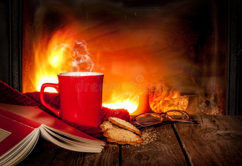 Tè o caffè caldo in una tazza, in un libro ed in un camino rossi
