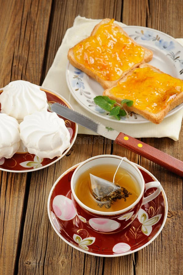 Tè verde, zefir e pani tostati con la marmellata di arance sulla parte posteriore di legno fotografia stock libera da diritti Tè verde, zefir e pani tostati con la marmellata di arance sulla parte posteriore di legno fotografia stock libera da diritti