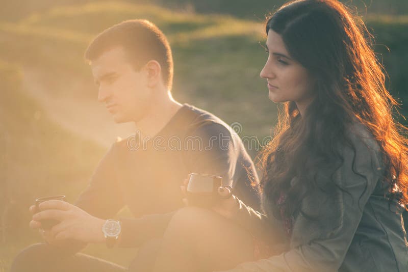 Té al aire libre de los pares jovenes cariñosos junto, de consumición feliz Un individuo con una muchacha en el lago en la puesta fotos de archivo libres de regalías Té al aire libre de los pares jovenes cariñosos junto, de consumición feliz Un individuo con una muchacha en el lago en la puesta fotos de archivo libres de regalías