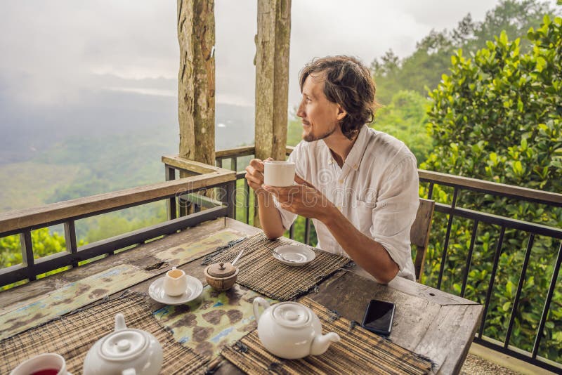 Té de consumición del hombre en un café en las montañas imagen de archivo libre de regalías Té de consumición del hombre en un café en las montañas imagen de archivo libre de regalías