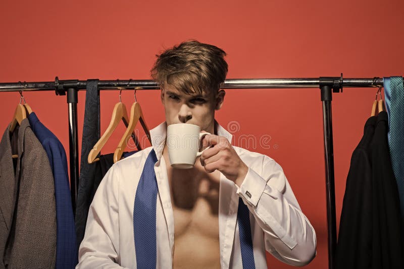 Té o café de la bebida del hombre de negocios en guardarropa en fondo rojo fotografía de archivo libre de regalías Té o café de la bebida del hombre de negocios en guardarropa en fondo rojo fotografía de archivo libre de regalías