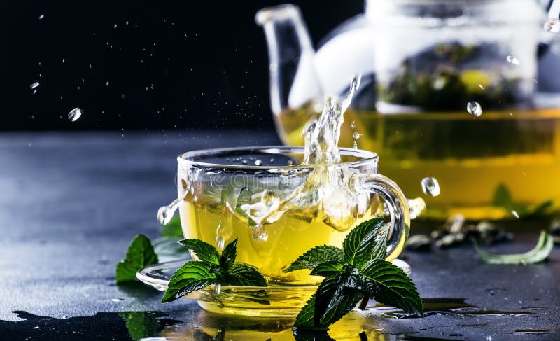 Té verde chino caliente con la menta, con el chapoteo vertiendo de KE foto de archivo Té verde chino caliente con la menta, con el chapoteo vertiendo de KE foto de archivo