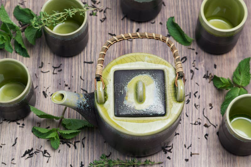 Té verde en tetera con las pequeñas tazas encima con la menta, fondo de madera imagenes de archivo Té verde en tetera con las pequeñas tazas encima con la menta, fondo de madera imagenes de archivo