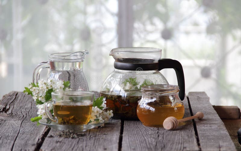 Té verde en una taza de cristal, miel y una rama de un espino floreciente fotos de archivo Té verde en una taza de cristal, miel y una rama de un espino floreciente fotos de archivo