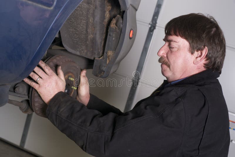 Auto technician works to repair problem with this car's brakes. Auto technician works to repair problem with this car's brakes.