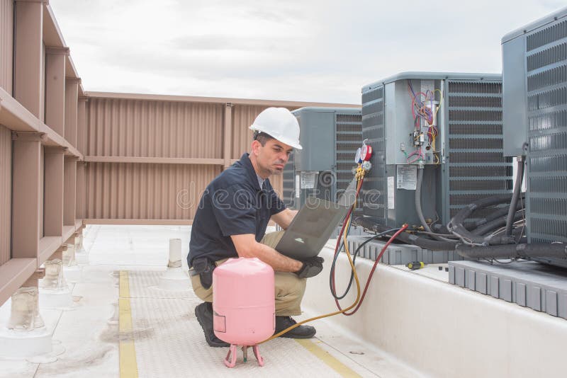 Technician looking at a panel off a condensing unit. Technician looking at a panel off a condensing unit.