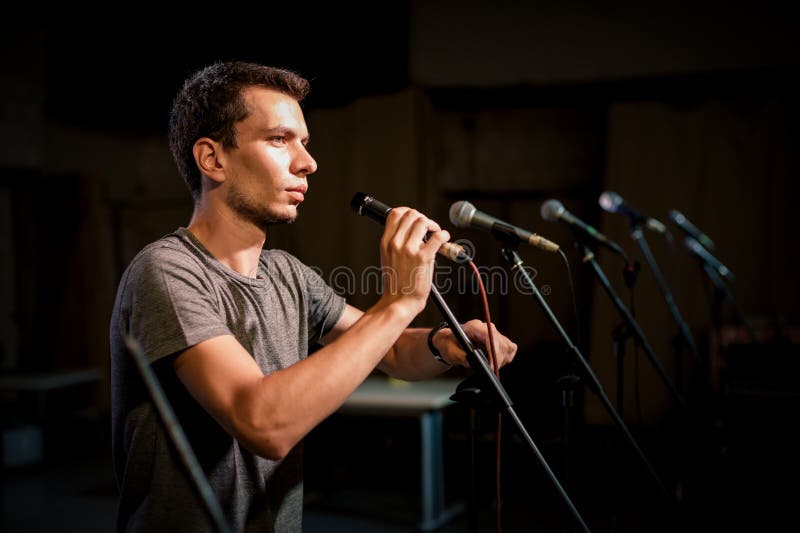 Técnico de audio de teatro ajustando un micrófono en la escena foto de archivo