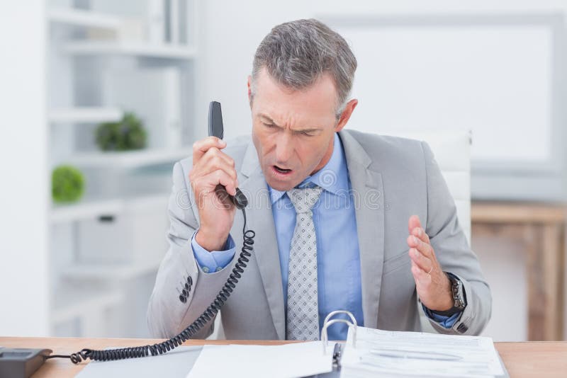 Téléphone de réponse irrité d'homme d'affaires images stock Téléphone de réponse irrité d'homme d'affaires images stock