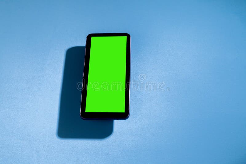 Téléphone portable avec écran vert sur une table bleue. concept smartphone. concept d'écran vert