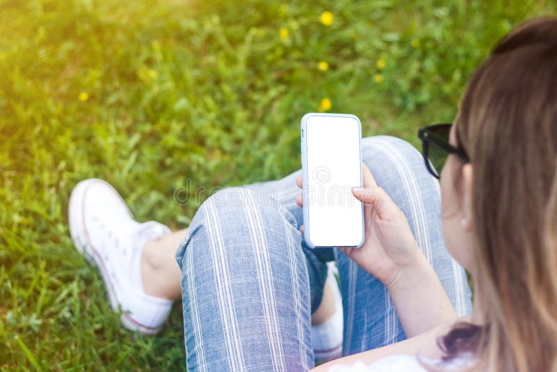 T?l?phone portable de participation de femme avec l'?cran vide dans sa main Fond d'herbe, rayons du soleil photos libres de droits T?l?phone portable de participation de femme avec l'?cran vide dans sa main Fond d'herbe, rayons du soleil photos libres de droits