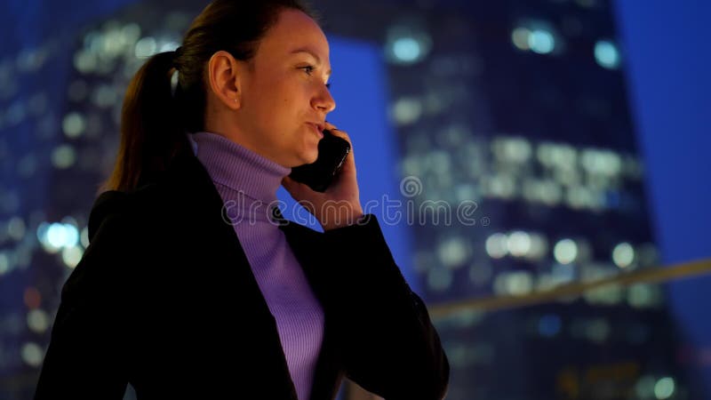 Téléphone portable parlant de femme d'affaires contre le gratte-ciel moderne