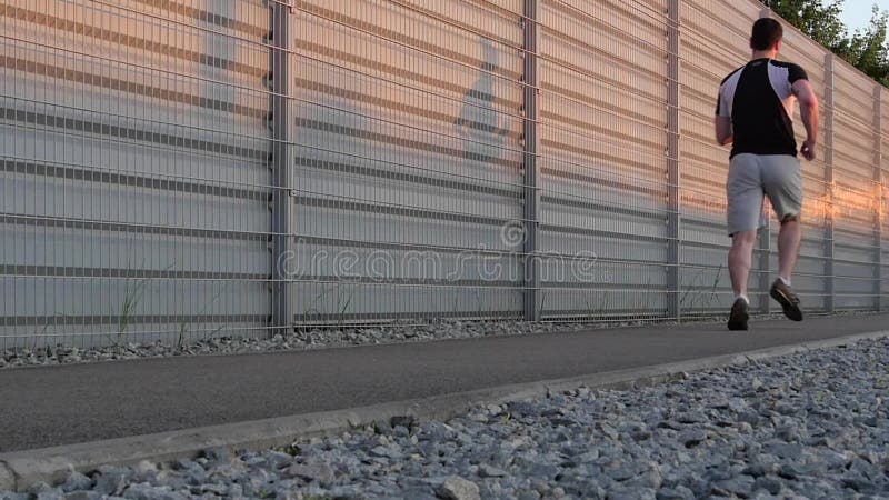 Tênis de corrida dos pés do corredor que correm na estrada com o close up na sapata Movimento lento