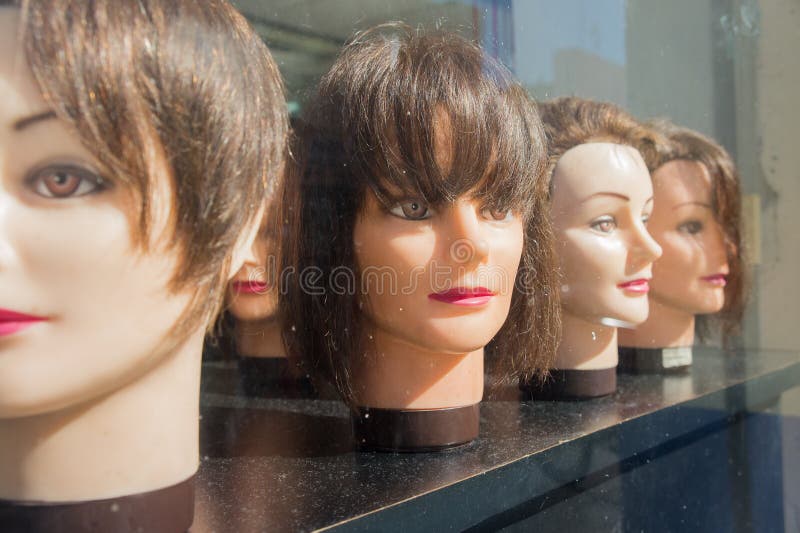 Female antique mannequin heads in window of cosmetology school and salon. Female antique mannequin heads in window of cosmetology school and salon