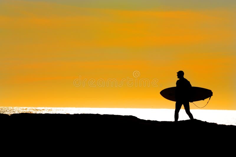 Surfer off of Point Santa Cruz in Northern California silhoutted as he is heading out for a last ride at sunset in December. Surfer off of Point Santa Cruz in Northern California silhoutted as he is heading out for a last ride at sunset in December