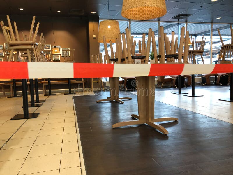 View beyond red white don´t cross line in empty closed restaurant with chairs stapled on tables during corona crisis royalty free stock photography View beyond red white don´t cross line in empty closed restaurant with chairs stapled on tables during corona crisis royalty free stock photography