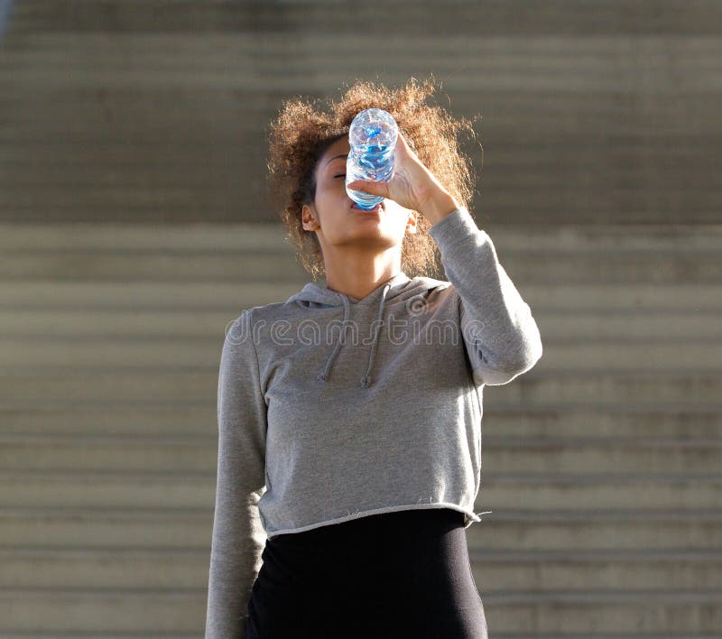 Törstig ung kvinna som dricker från vattenflaskan