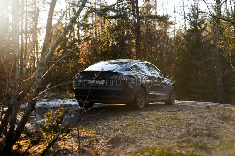 TÃ¸nsberg, Norway - march 18, 2021: black Tesla model 3 Long Range Dual motor is an electric car with  forest