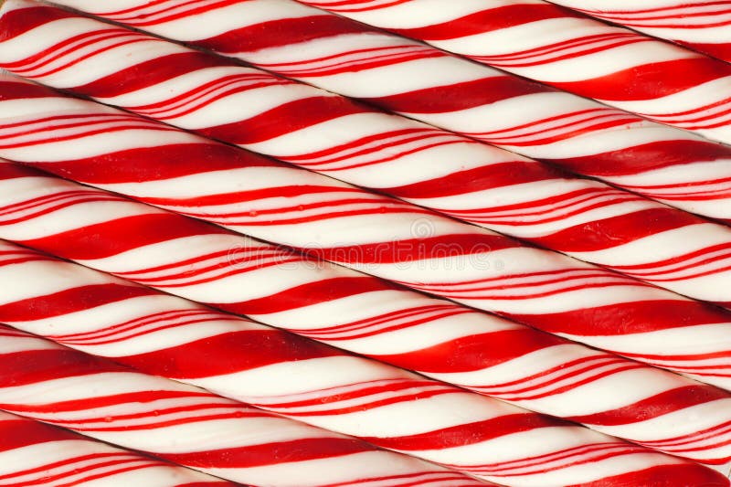 Full background of red and white striped Christmas candy canes at a diagonal. Full background of red and white striped Christmas candy canes at a diagonal