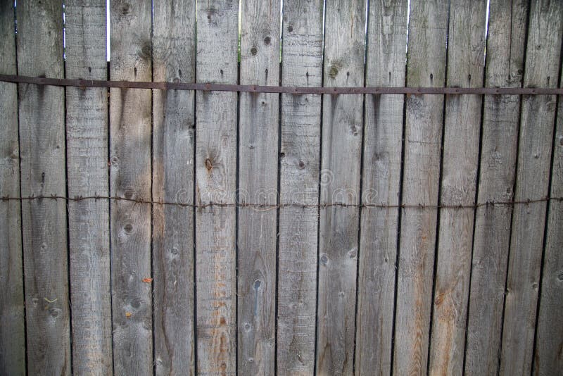 Background of the fence gray boards with knots hammered metal tape barbed  wire. Design backgrounds texture. Background of the fence gray boards with knots hammered metal tape barbed  wire. Design backgrounds texture.