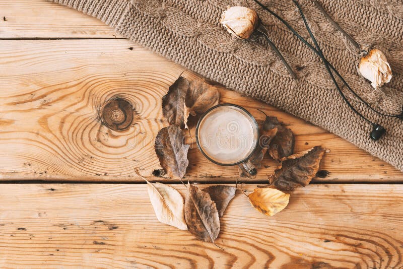 Fall background. Coffee, fall leaves and knitted sweater. A cup of coffee and knitted scarf on wooden table. Drinking coffee and listening to music. Autumn Chill-out, Fall season relax concept. Fall background. Coffee, fall leaves and knitted sweater. A cup of coffee and knitted scarf on wooden table. Drinking coffee and listening to music. Autumn Chill-out, Fall season relax concept