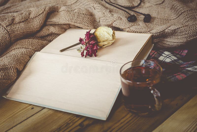 Fall background. Autumn composition with hot tea, book, dry rose flower and knitted sweater. A cup of hot tea, knitted scarf on wooden table. Autumn reading list. Weekend leisure at fall season. Fall background. Autumn composition with hot tea, book, dry rose flower and knitted sweater. A cup of hot tea, knitted scarf on wooden table. Autumn reading list. Weekend leisure at fall season