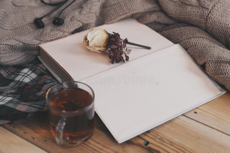 Fall background. Autumn composition with hot tea, book, dry rose flower and knitted sweater. A cup of hot tea, knitted scarf on wooden table. Autumn reading list. Weekend leisure at fall season. Fall background. Autumn composition with hot tea, book, dry rose flower and knitted sweater. A cup of hot tea, knitted scarf on wooden table. Autumn reading list. Weekend leisure at fall season