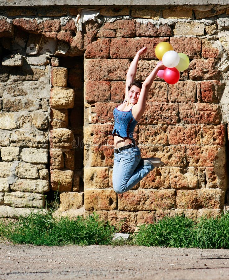 Happy girl jumping with balloons on grunge background. Happy girl jumping with balloons on grunge background