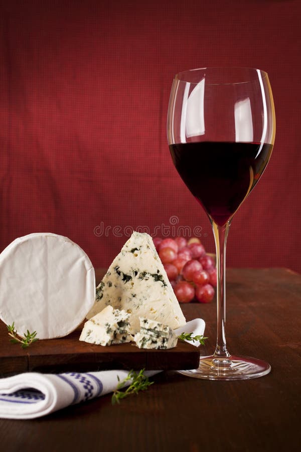 Traditional dark red wine background with blue cheese and grapes on dark wooden background. Traditional dark red wine background with blue cheese and grapes on dark wooden background.
